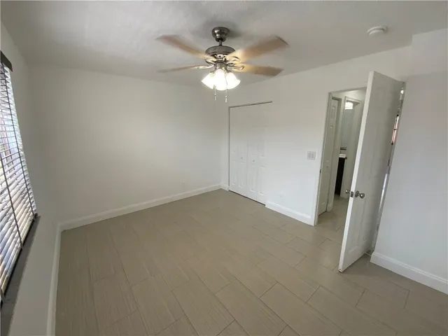 an empty room with a chandelier fan and windows