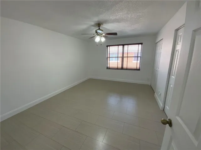 an empty room with a window and a fan