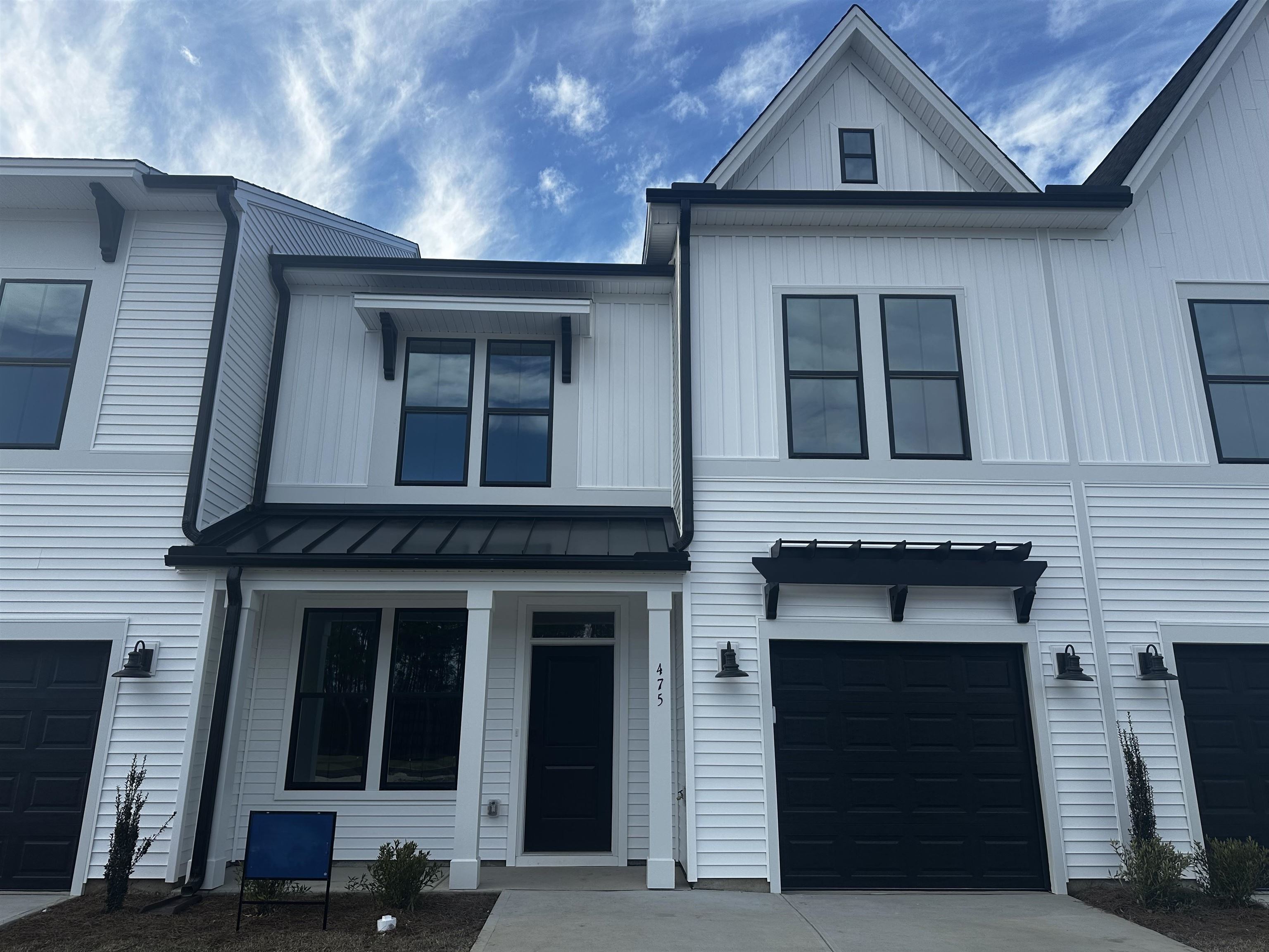Modern farmhouse style home featuring board and batten siding, a standing seam roof, a metal roof, and a garage