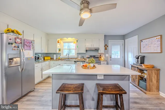 a kitchen with stainless steel appliances granite countertop a stove a refrigerator a sink a dining table and chairs with wooden floor