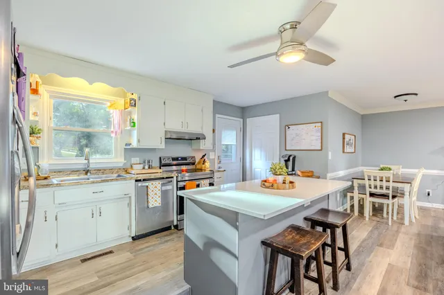 a kitchen with a dining table chairs and white appliances