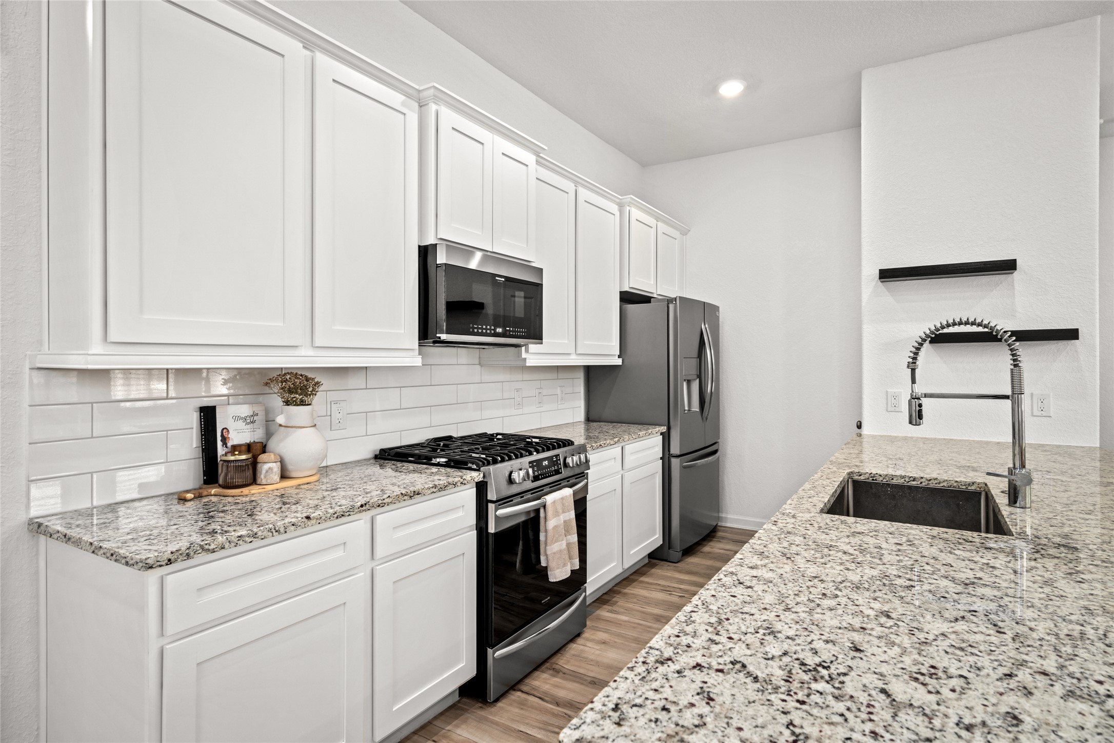 575 Dry Fork Lane Conroe, TX 77304 - Photo 7 of 34 Custom tile backsplash, granite countertops, and upgraded appliances highlight the kitchen.