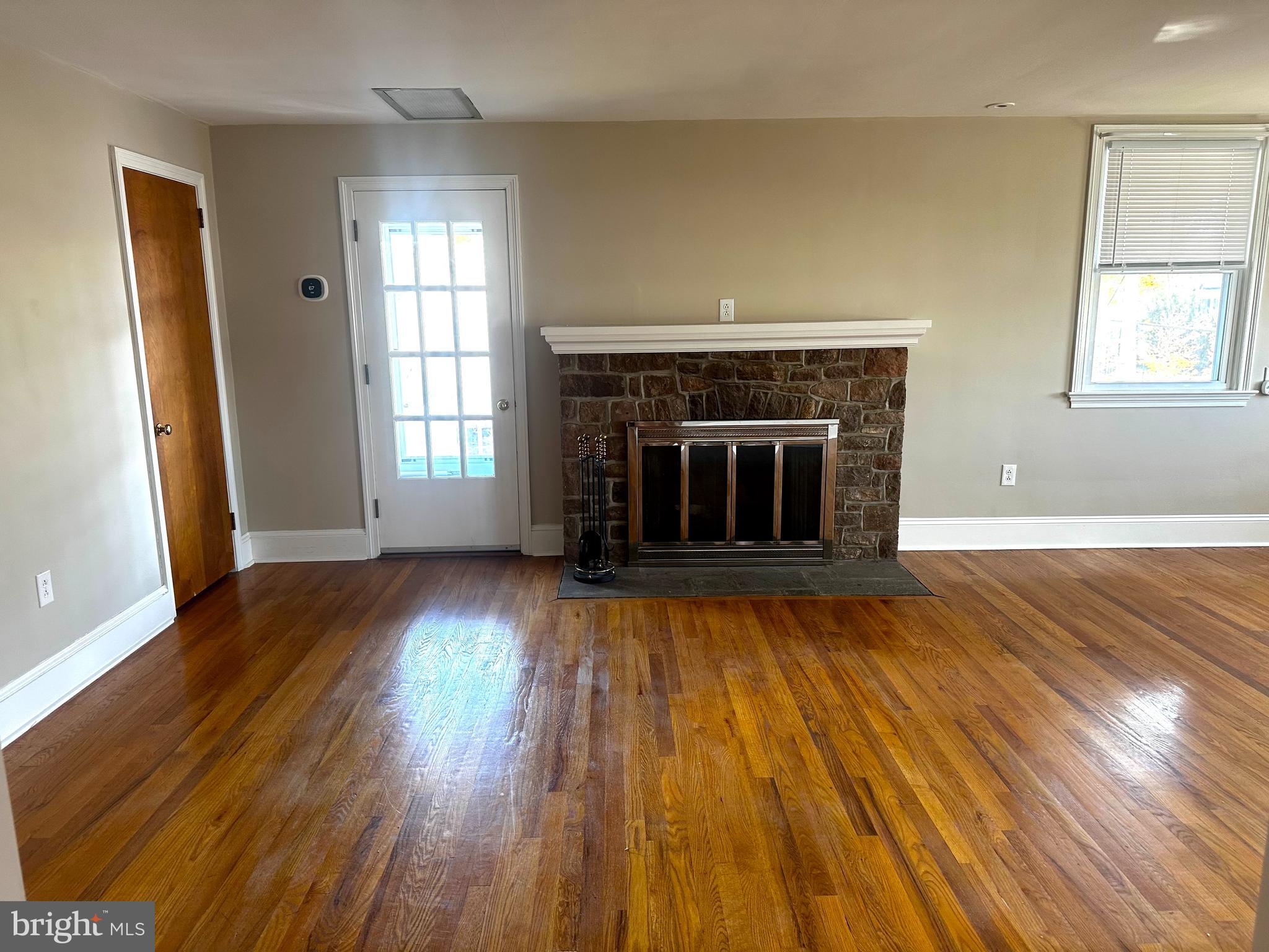 an empty room with wooden floor fireplace and windows