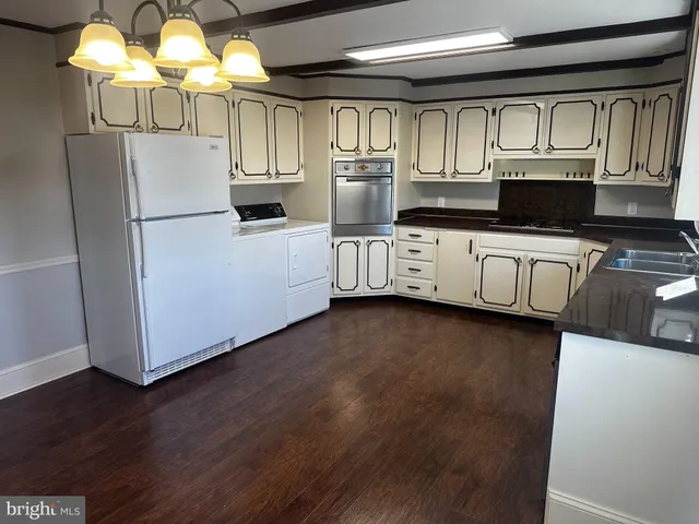 a kitchen with stainless steel appliances granite countertop a refrigerator oven a sink dishwasher and white cabinets with wooden floor