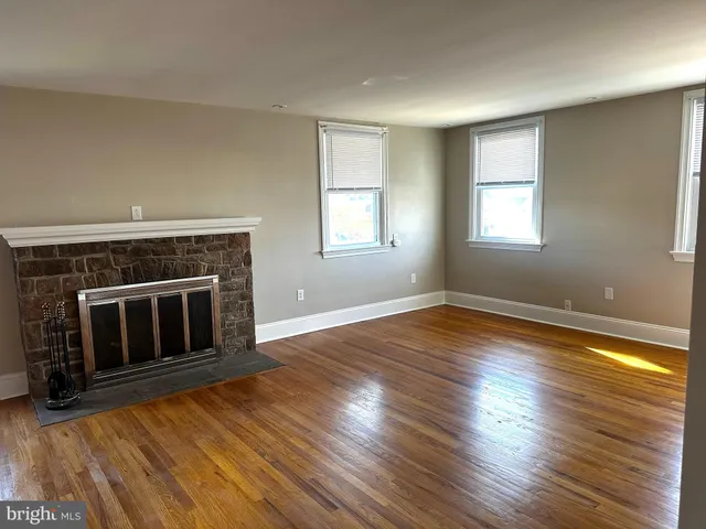 an empty room with wooden floor fireplace and windows