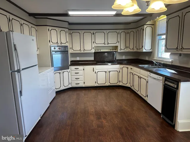 a kitchen with stainless steel appliances granite countertop a refrigerator a stove a sink and dishwasher with wooden floor