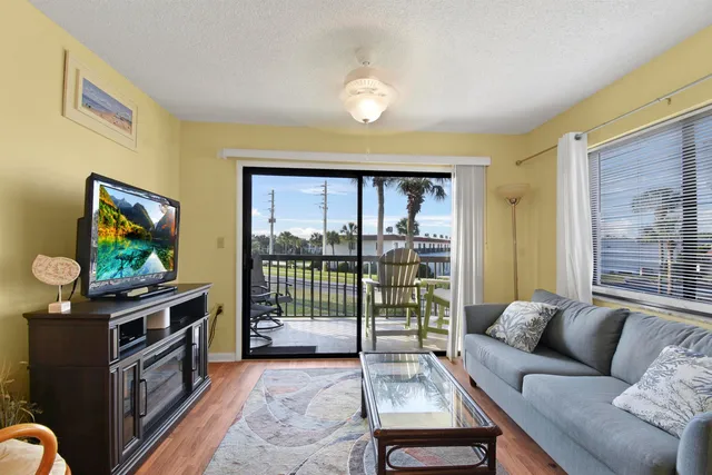a living room with furniture a flat screen tv and a floor to ceiling window