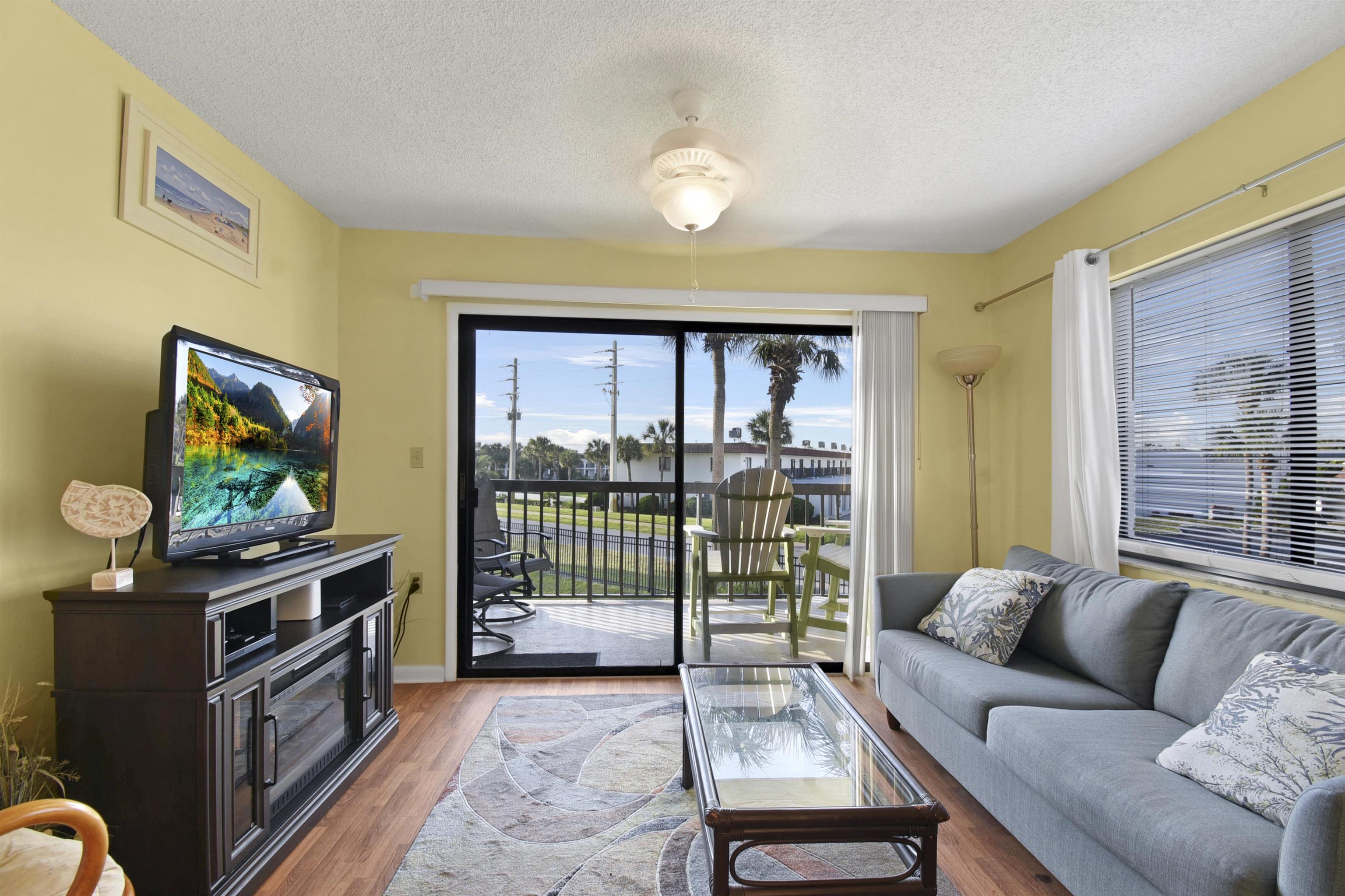 4250 A1A South, Unit C26 St. Augustine, FL 32080 - Photo 4 of 39 a living room with furniture a flat screen tv and a floor to ceiling window
