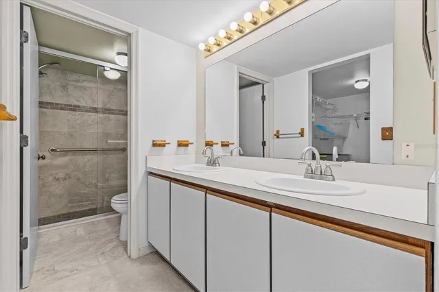 a bathroom with a double vanity sink toilet and shower
