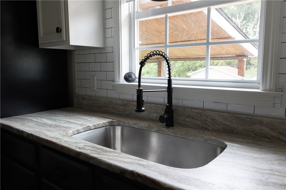 439 Chetola Road Seneca, SC 29672 - Photo 5 of 28 Natural stone countertops surround an undermount stainless steel sink positioned beneath a classic multi-pane window.