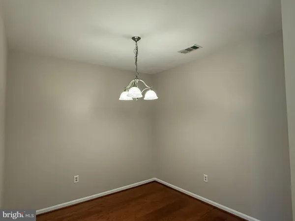 a view of a room with a chandelier fan and wooden floor