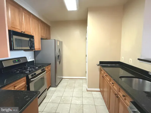 a kitchen with granite countertop a refrigerator stove and microwave