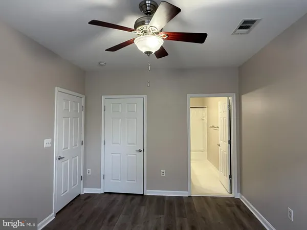 an empty room with wooden floor fan and windows