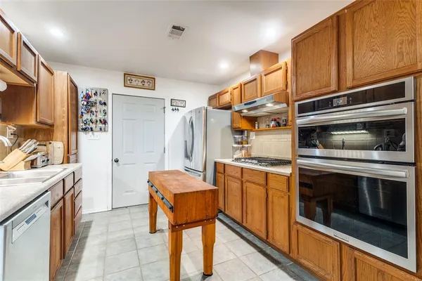 a kitchen with stainless steel appliances kitchen island granite countertop a stove and a refrigerator