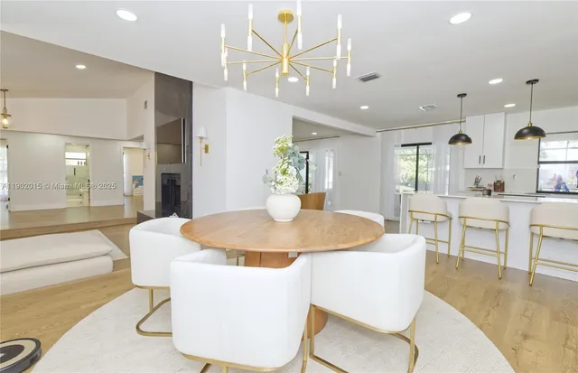 a dining room with kitchen island stainless steel appliances furniture a chandelier open kitchen view