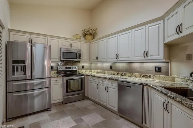 a kitchen with granite countertop a sink stainless steel appliances and cabinets