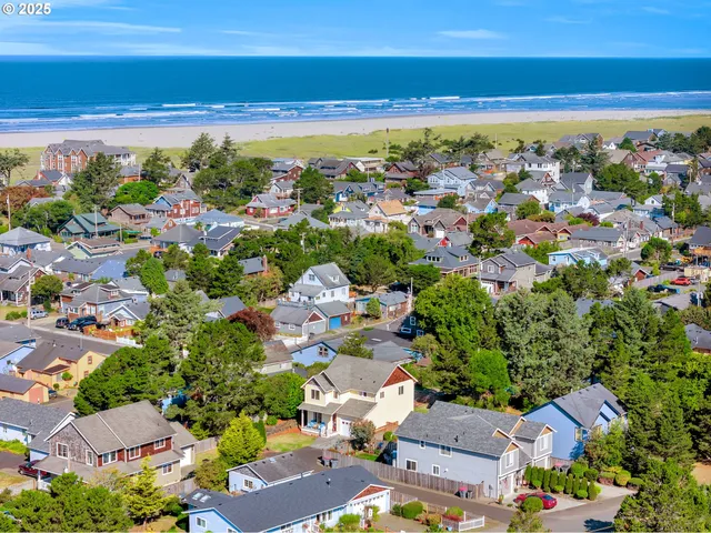 an aerial view of a city with lots of residential buildings ocean and mountain view in back
