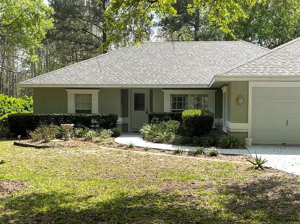 a view of a house with snow on the ground and large trees