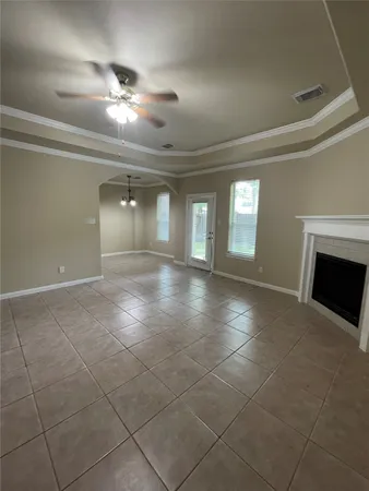 a view of an empty room with a fireplace and chandelier fan