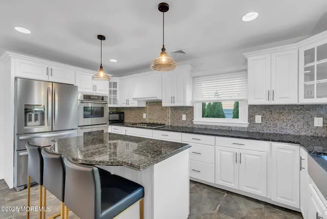 a kitchen with stainless steel appliances granite countertop a sink a stove a refrigerator and island