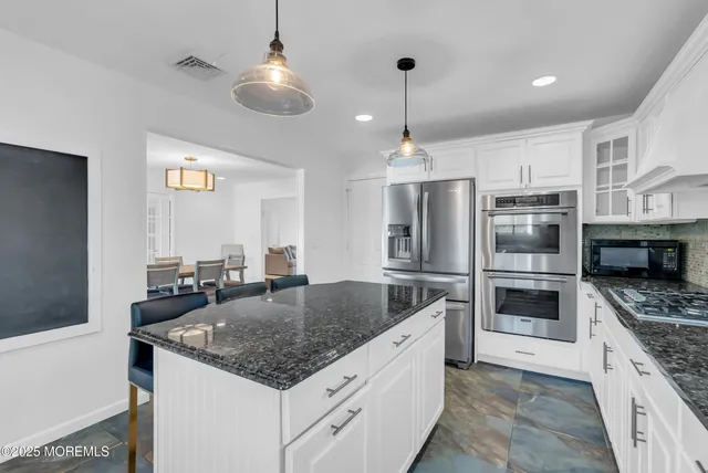 a kitchen with stainless steel appliances granite countertop a sink and a refrigerator