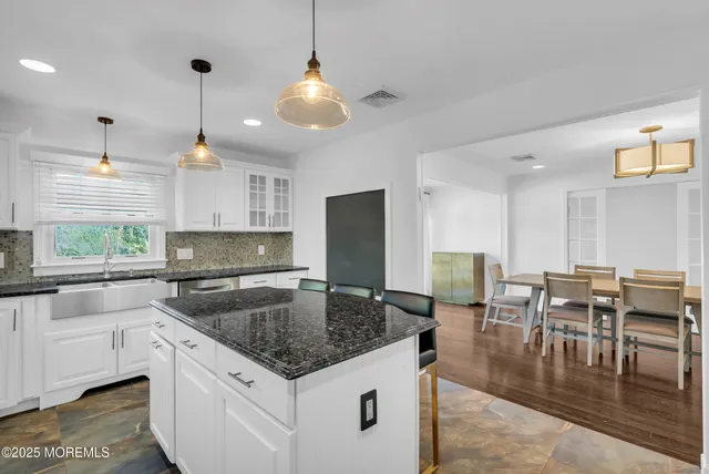 a kitchen with stainless steel appliances granite countertop a stove top oven a sink a dining table and chairs