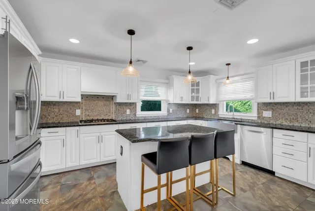 a kitchen with stainless steel appliances granite countertop a sink a stove a center island and cabinets