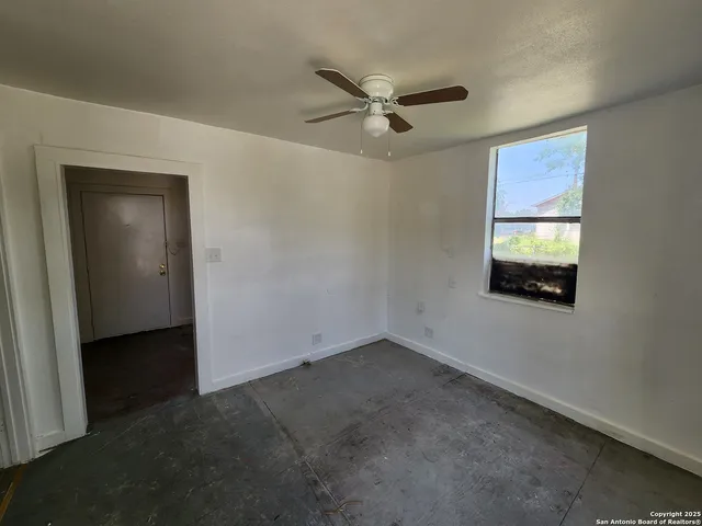 an empty room with a window and a ceiling fan