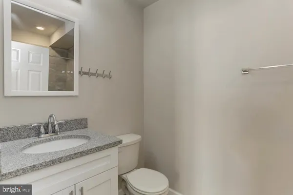 a bathroom with a granite countertop toilet sink and mirror