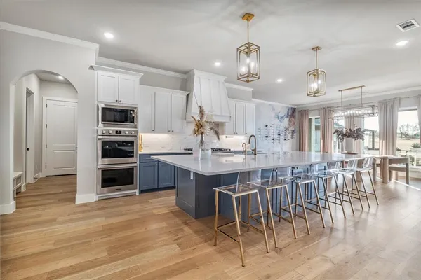 a kitchen with stainless steel appliances kitchen island granite countertop a table chairs sink and cabinets