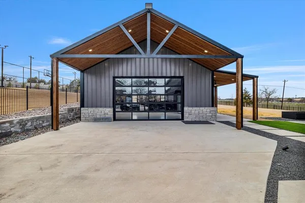 a front view of a house with large trees and cars parked in front of it