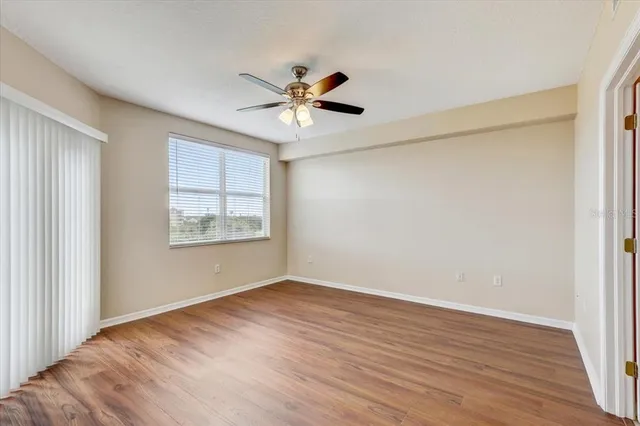 a view of an empty room with a window and wooden floor