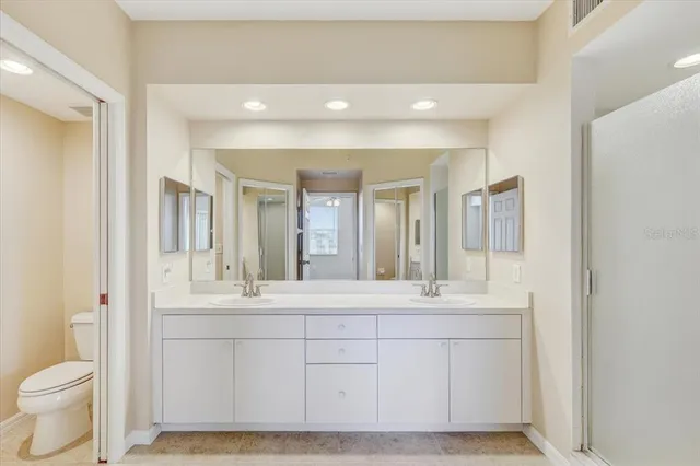 a bathroom with a double vanity sink mirror and toilet