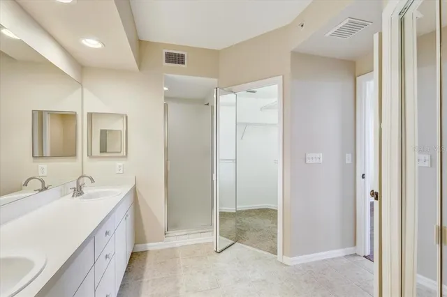 a spacious bathroom with a double vanity sink a mirror and a shower