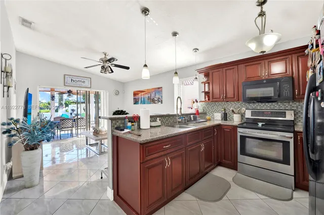 a kitchen with kitchen island granite countertop a sink cabinets and stainless steel appliances