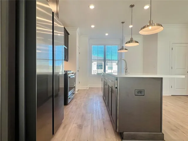 a kitchen with stainless steel appliances granite countertop a refrigerator and a wooden floor
