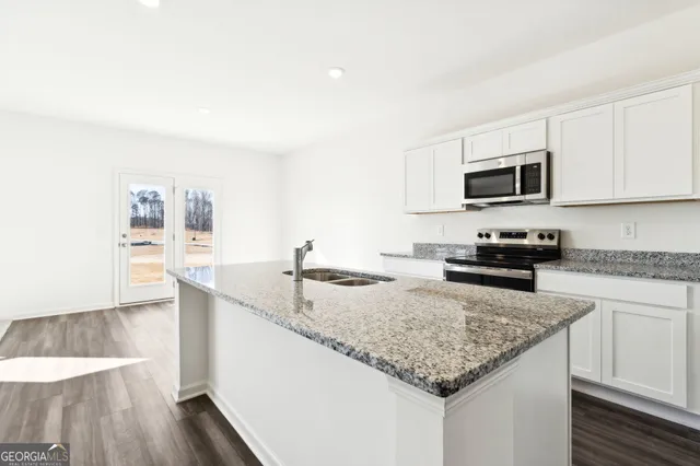 a kitchen with granite countertop a sink dishwasher stove and microwave with wooden floor