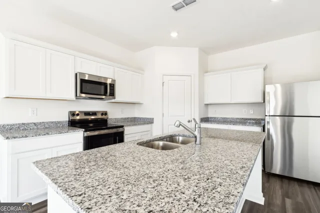 a kitchen with stainless steel appliances granite countertop a sink stove and refrigerator