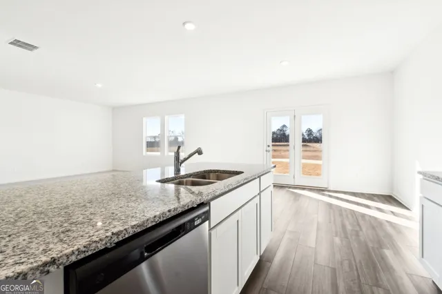 a kitchen with granite countertop a sink a stove cabinets and wooden floor