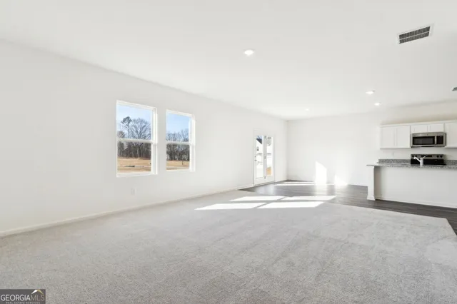 a view of empty room with kitchen and window