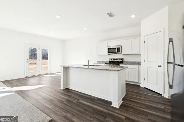 a kitchen with granite countertop a refrigerator and a stove top oven