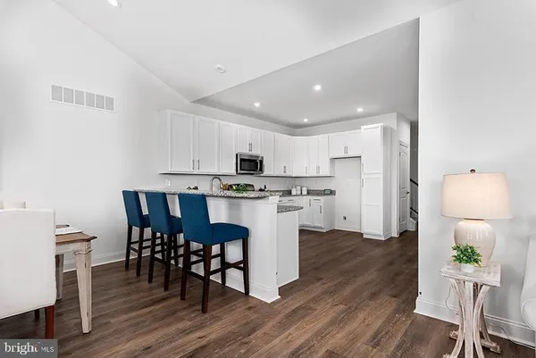 a kitchen with stainless steel appliances a dining table chairs stove refrigerator and microwave