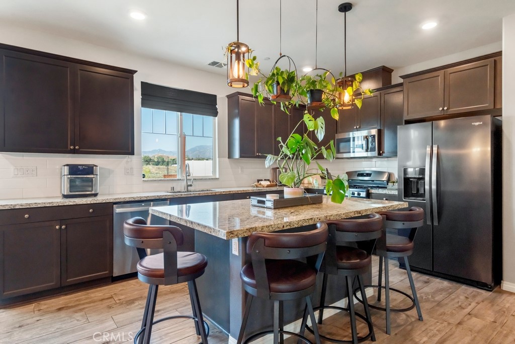 1148 Little Leaf Street Calimesa, CA 92320 - Photo 5 of 31 a kitchen with stainless steel appliances granite countertop a refrigerator a sink dishwasher a dining table and chairs with wooden floor