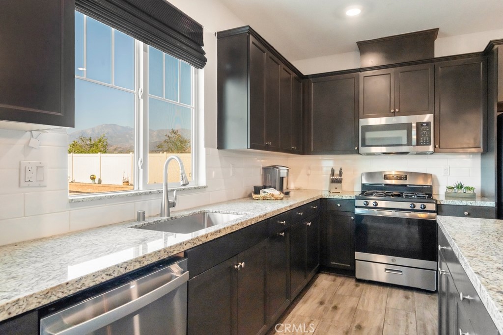 1148 Little Leaf Street Calimesa, CA 92320 - Photo 6 of 31 a kitchen with stainless steel appliances granite countertop a sink a stove a microwave and wooden cabinets