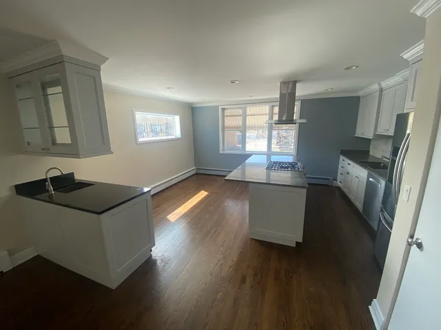 a kitchen with granite countertop a sink and wooden floors