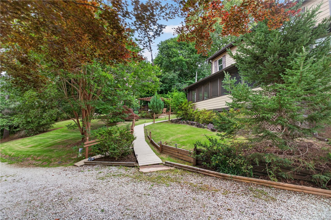 351 River Road Westminster, SC 29693 - Photo 3 of 50 A winding pathway leads through lush greenery to a charming screened porch.