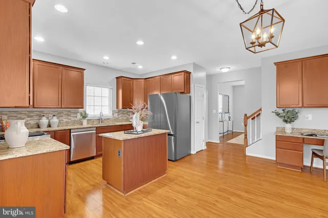 a kitchen with stainless steel appliances granite countertop a sink a stove a refrigerator cabinets and wooden floor