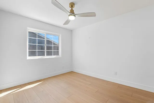 an empty room with a window and ceiling fan