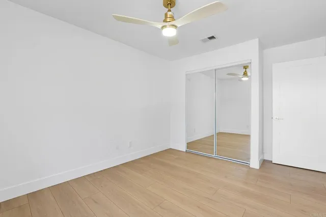 an empty room with closet and a ceiling fan