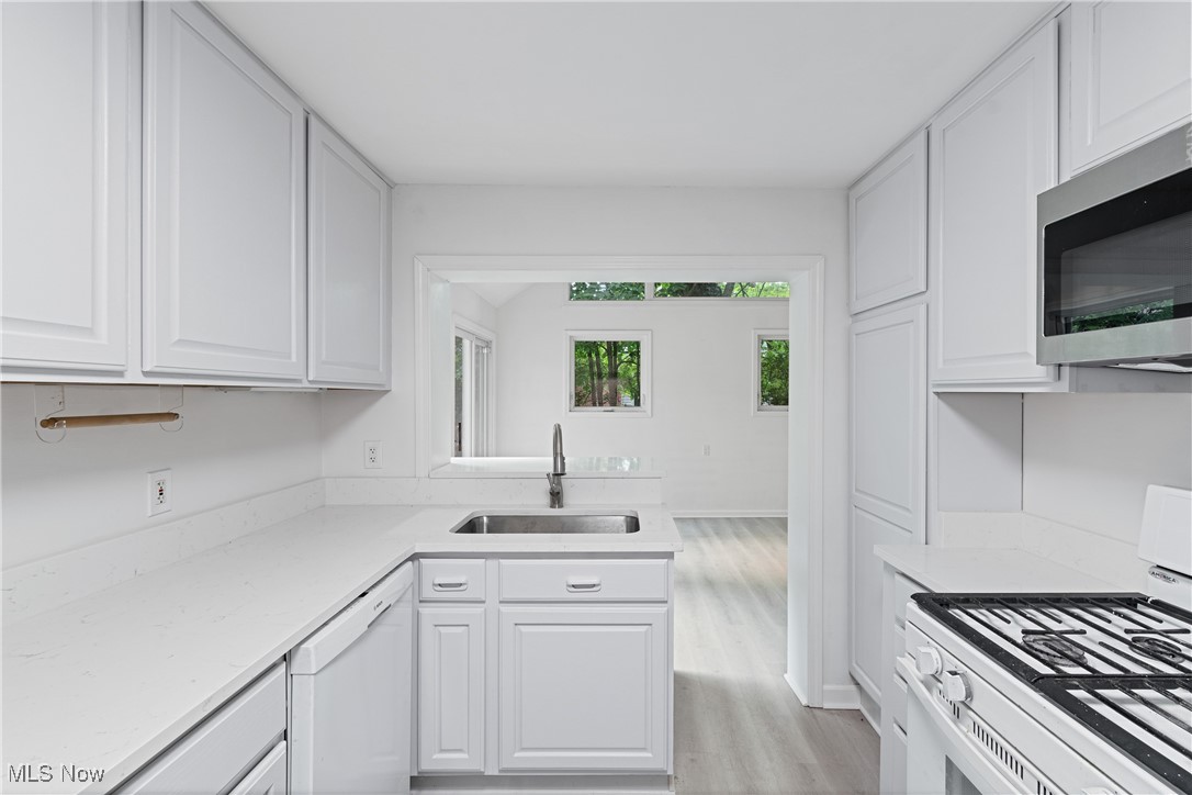 1057 Renfield Road Cleveland Heights, OH 44121 - Photo 11 of 30 Kitchen with white cabinets, white appliances, light stone countertops, light hardwood / wood-style floors, and sink